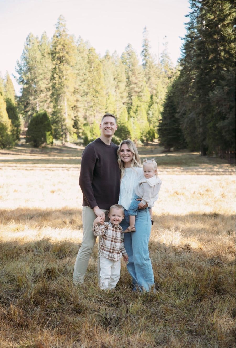The PAKD founders and their two young children standing in a golden mountain meadow surrounded by pine trees